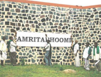 I contadini del Centro Internazionale AMRITA BHOOMI fissano lo striscione con il nome del Centro sul muro esterno.
